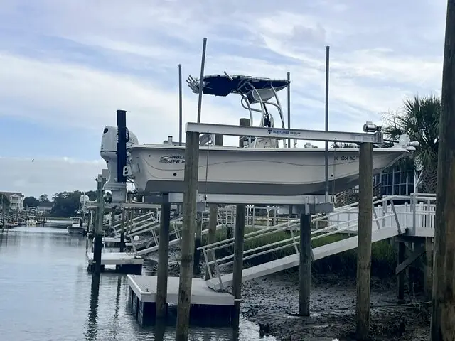 Boat raised on a lift beside an aluminum pier on a canal