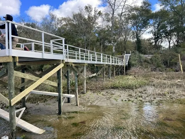 Elevated aluminum pier on wood pilings crossing low marsh
