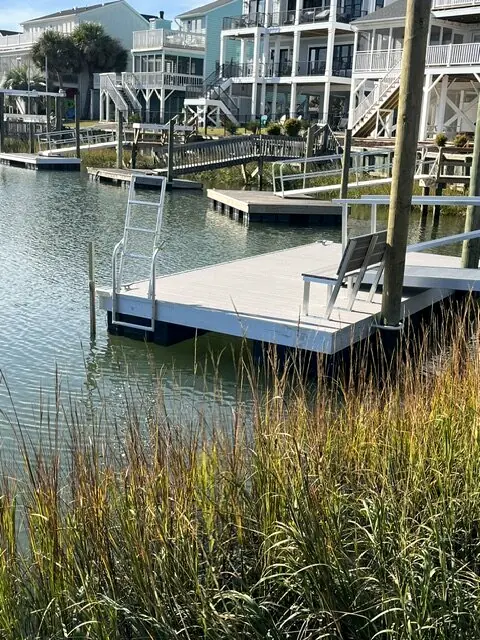 Floating dock with a built-in bench set in marsh grass along a canal of beach homes