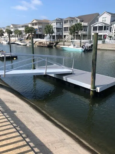 Aluminum gangway and floating dock on a calm canal lined with homes