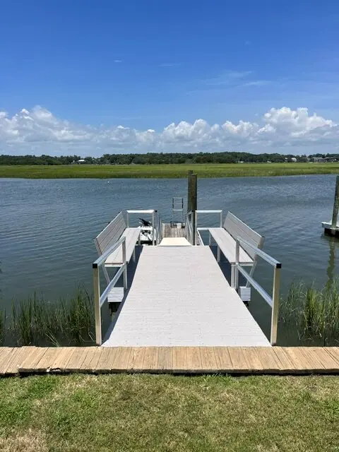 Aluminum gangway leading to a floating dock across marsh grass under a clear sky