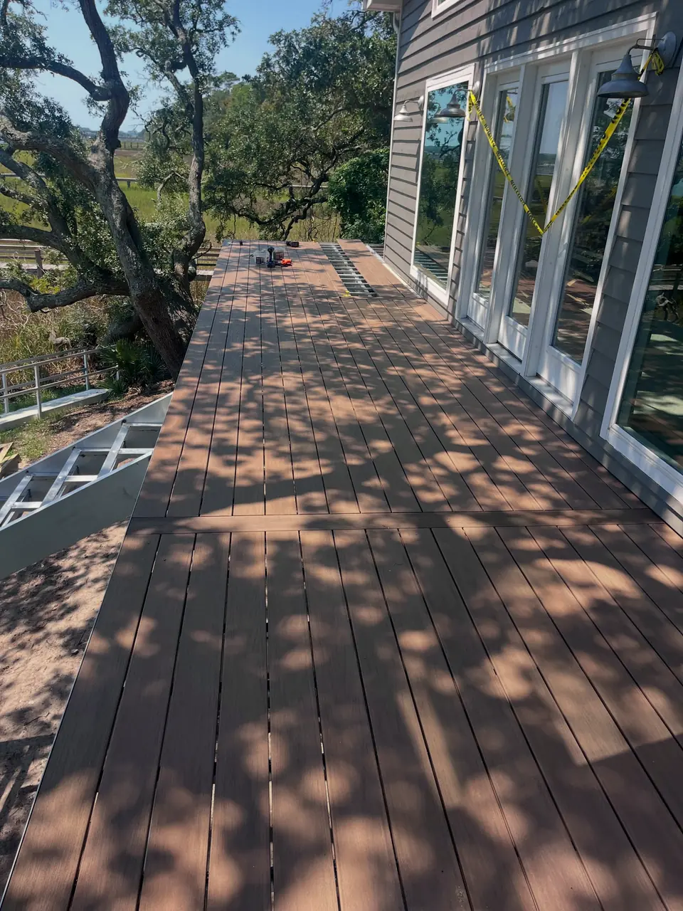 New composite deck on aluminum framing beside a home under live oaks