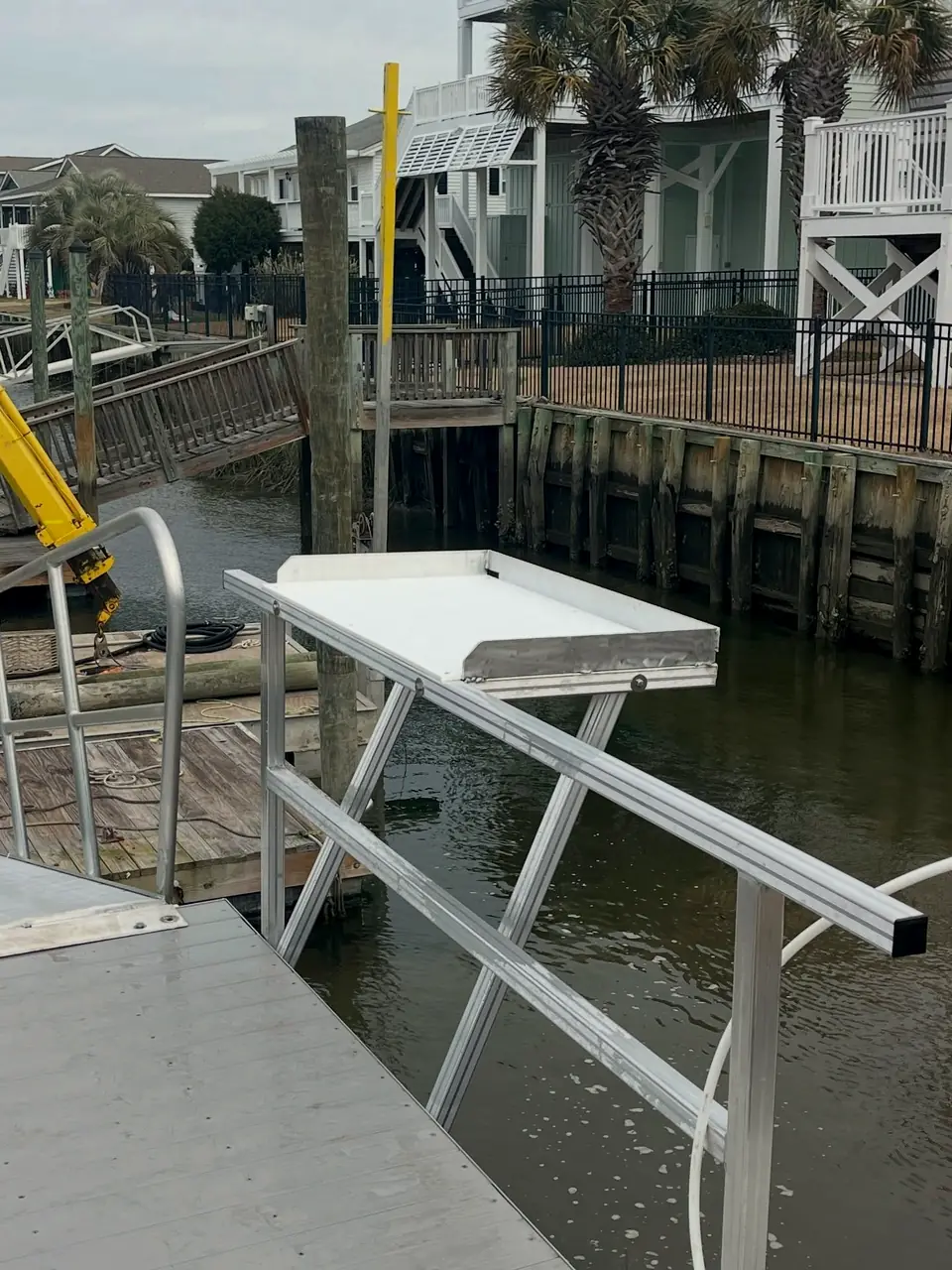 Aluminum fish cleaning station with a cutting board beside a canal
