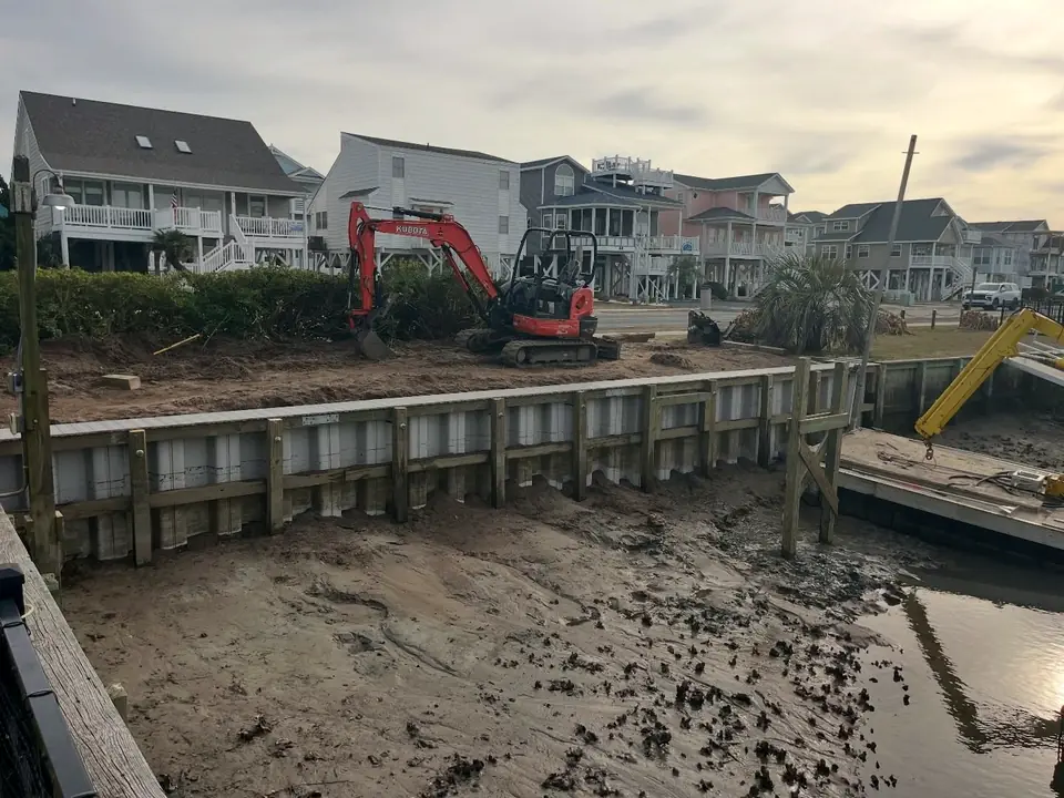New vinyl seawall at low tide with equipment finishing the backfill