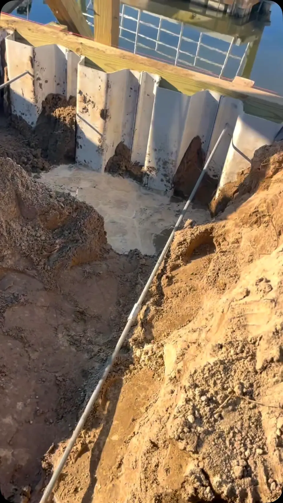 Vinyl seawall sheet piling being set in an excavated trench