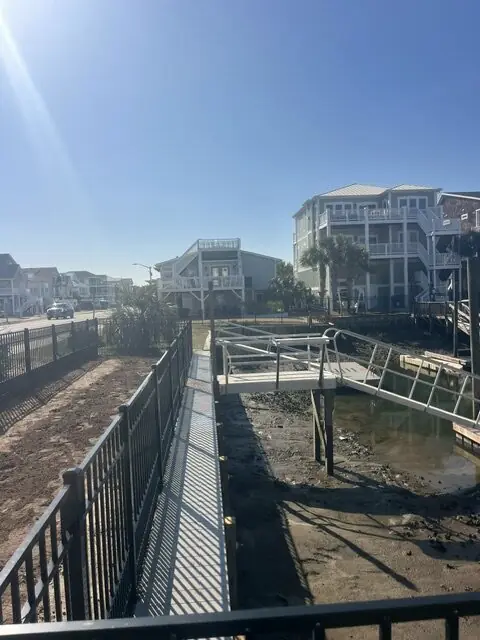 Aluminum walkway with black railing running along a new seawall toward the water