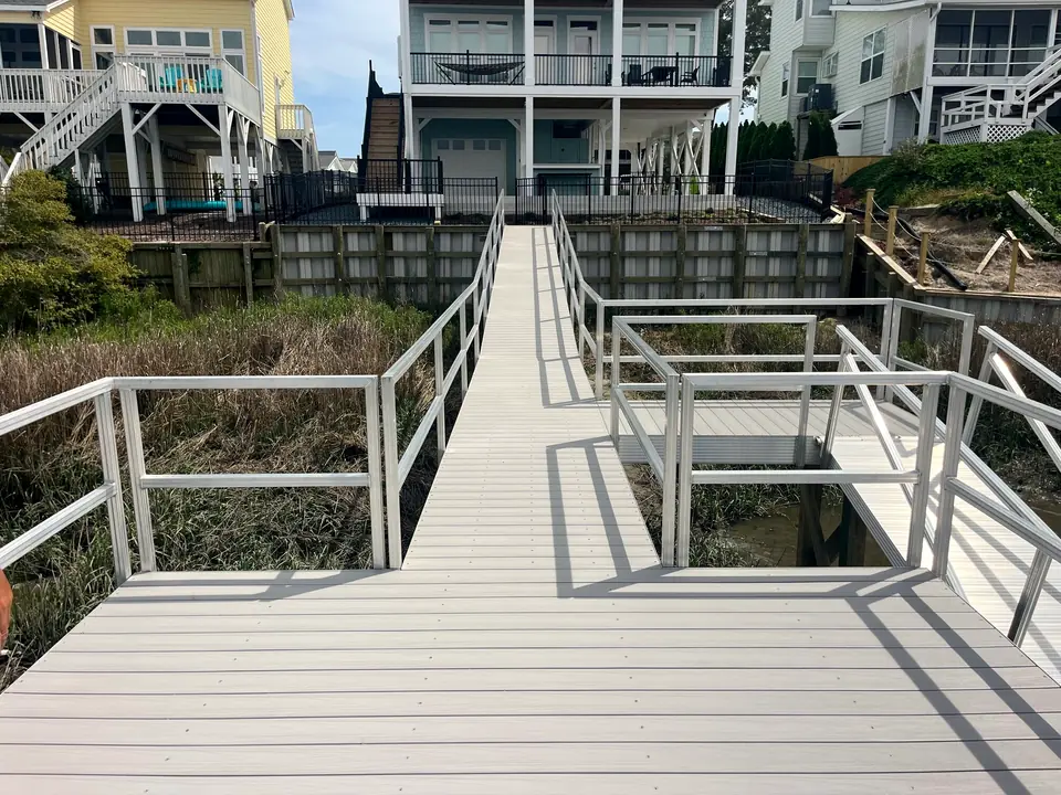Composite-decked walkway with aluminum railings running from a home over a new seawall toward the water