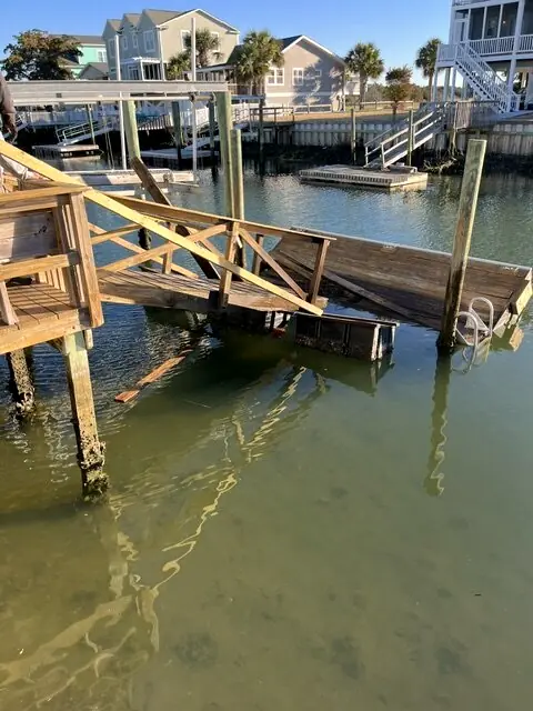 Storm-damaged wooden dock and stairs collapsed toward the water before repair